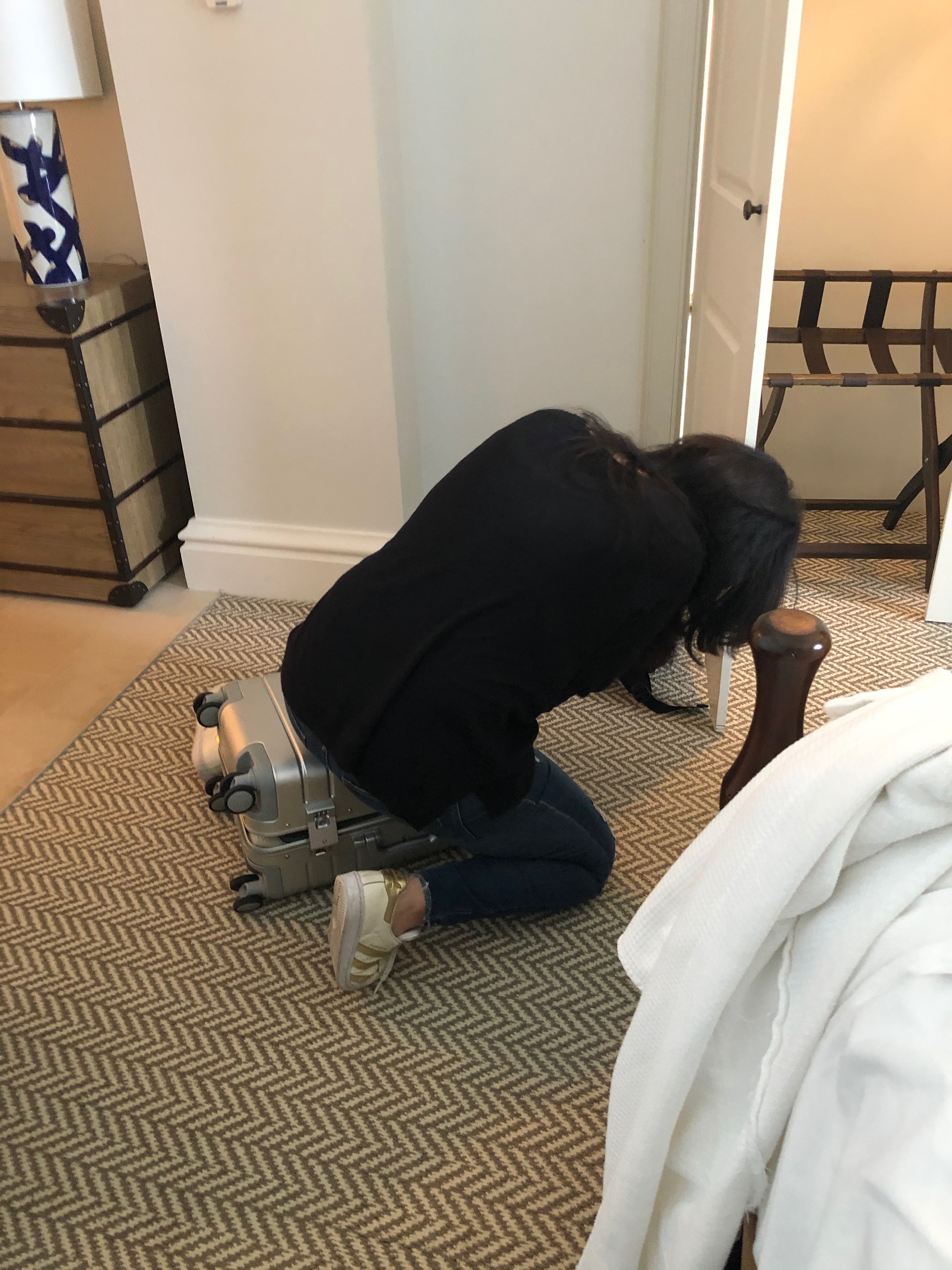 Kandi trying to close a packed suitcase