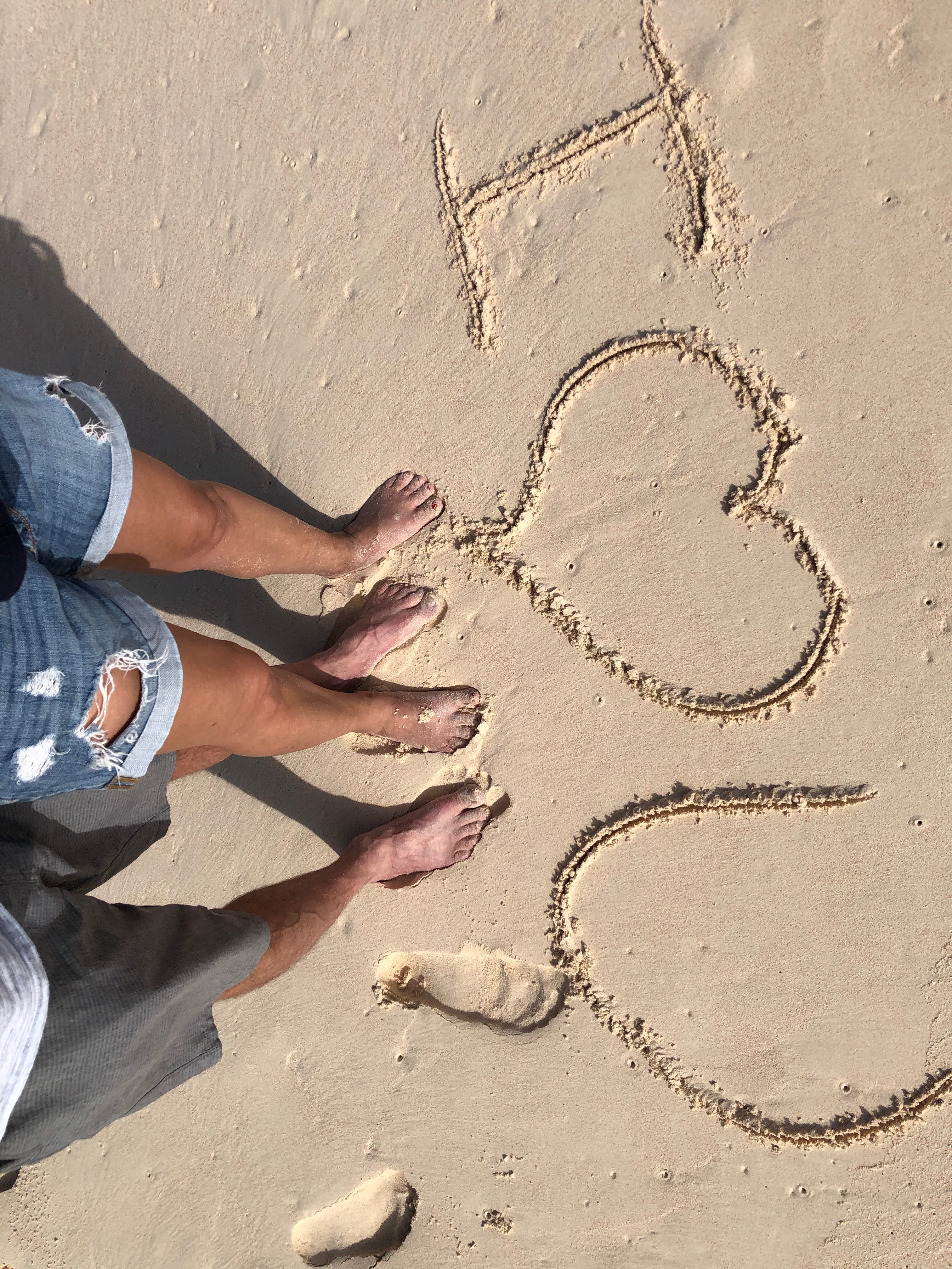 Feet beside I love you written in the sand